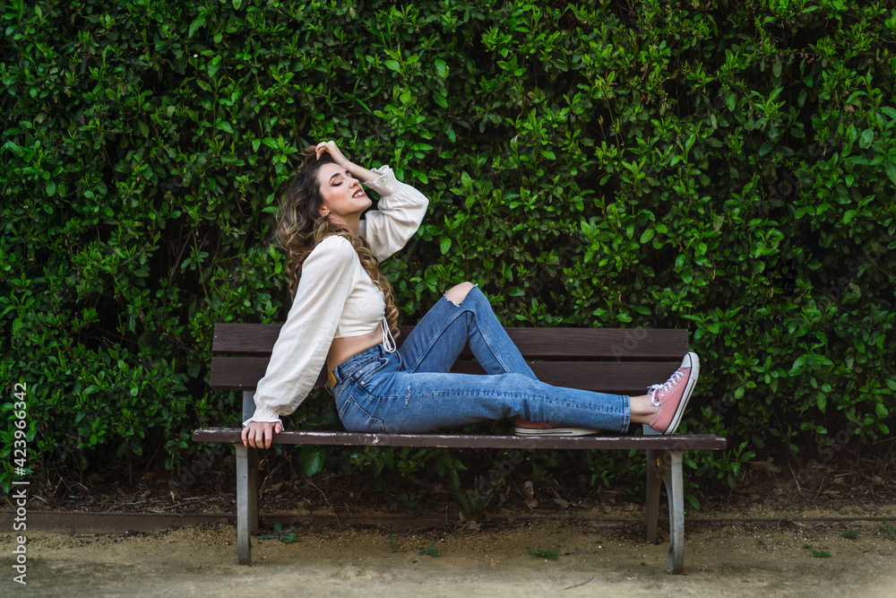 Chica en un banco en un parque verde en primavera Chica en un banco en un parque verde en primavera