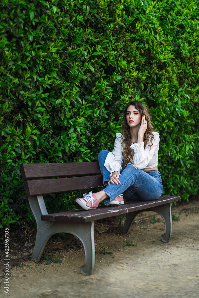 Chica en un banco en un parque verde en primavera Chica en un banco en un parque verde en primavera