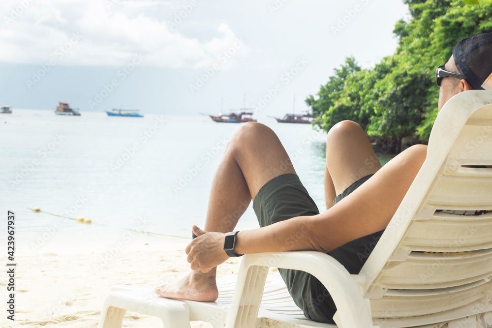Male Asian tourists lie on beach chairs, sea views, and Thai long-tailed boats.