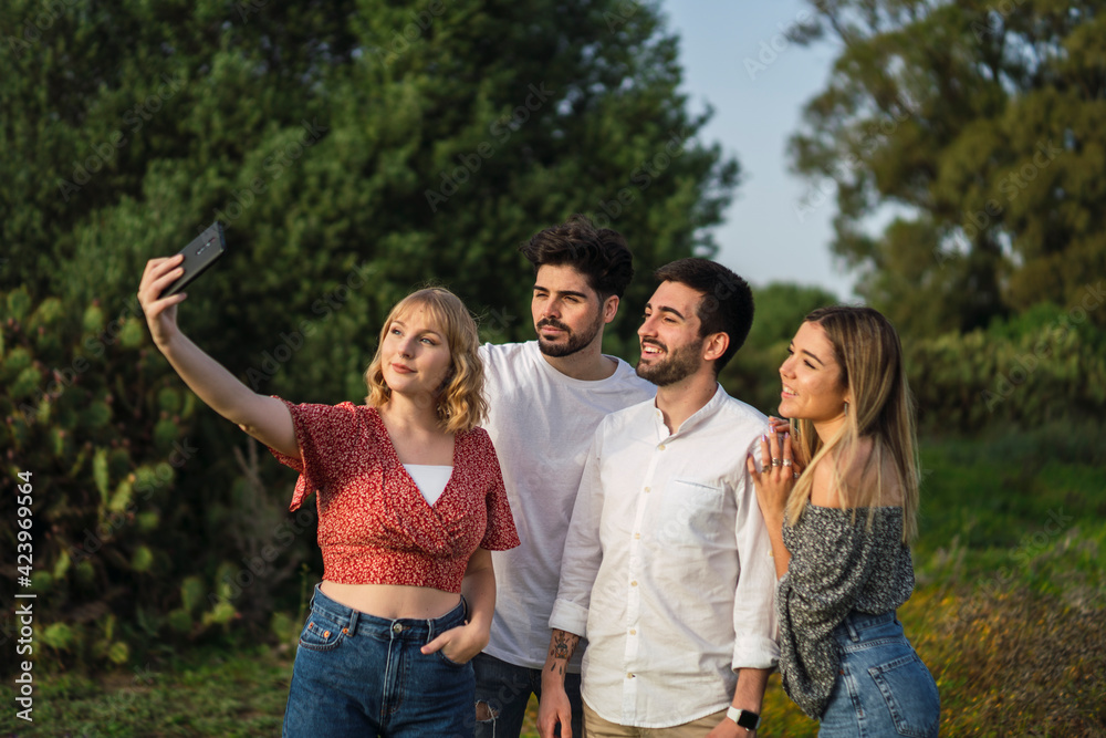 Grupo de amigos disfrutando de zona verde en primavera tomando selfies