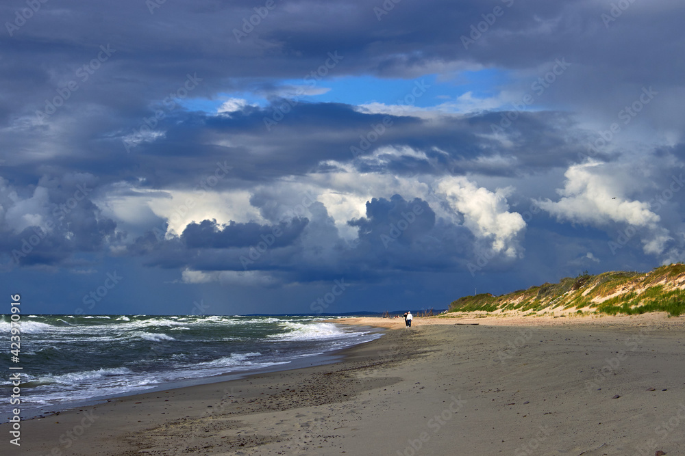 Blue dramatic clouds and sunbeams break through over the beach