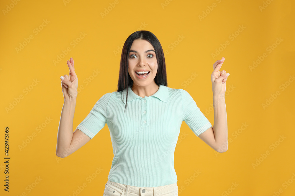 Woman with crossed fingers on yellow background. Superstition concept Woman with crossed fingers on yellow background. Superstition concept