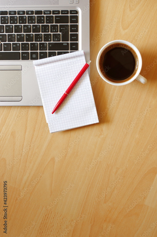 Laptop with coffee cup, notebook and pen on wooden background Top view. Concept for home office. Business concept. Work from home. Desk with laptop, blank notepad, coffee cup and pen on wooden table. Laptop with coffee cup, notebook and pen on wooden background Top view. Concept for home office. Business concept. Work from home. Desk with laptop, blank notepad, coffee cup and pen on wooden table.