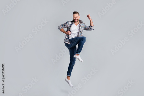 Full length body size photo of jumping man in casual outfit gesturing like winner isolated grey color background