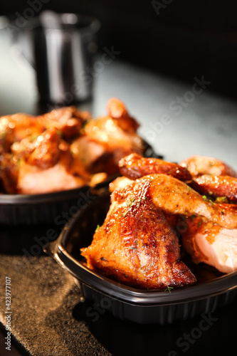 Cooked pieces of grilled chicken in plastic containers on bar counter. Food delivery service