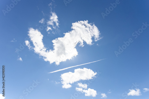 Blue sky with interesting cloud formations and vapour trail - chemtrail