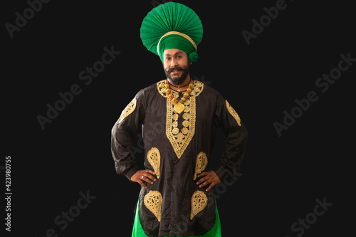 A man in Bhangra Costume standing with hands on his waist. 