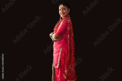 A woman in a Giddha costume standing with hands folded.	 photo