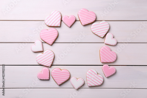 Frame of glazed heart shaped cookies on white wooden table, flat lay. Space for text