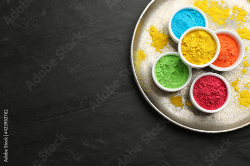 Colorful powder dyes on black background, top view with space for text. Holi festival
