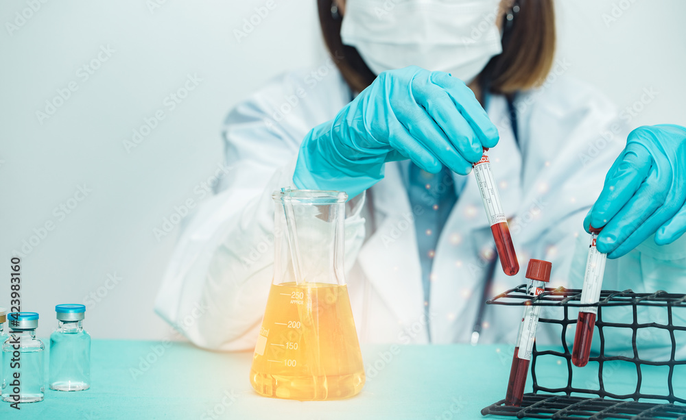 Doctor hand taking a blood test tube from a rack of analysis in a sterile room. Technician holding blood tube test in the research laboratory Doctor hand taking a blood test tube from a rack of analysis in a sterile room. Technician holding blood tube test in the research laboratory