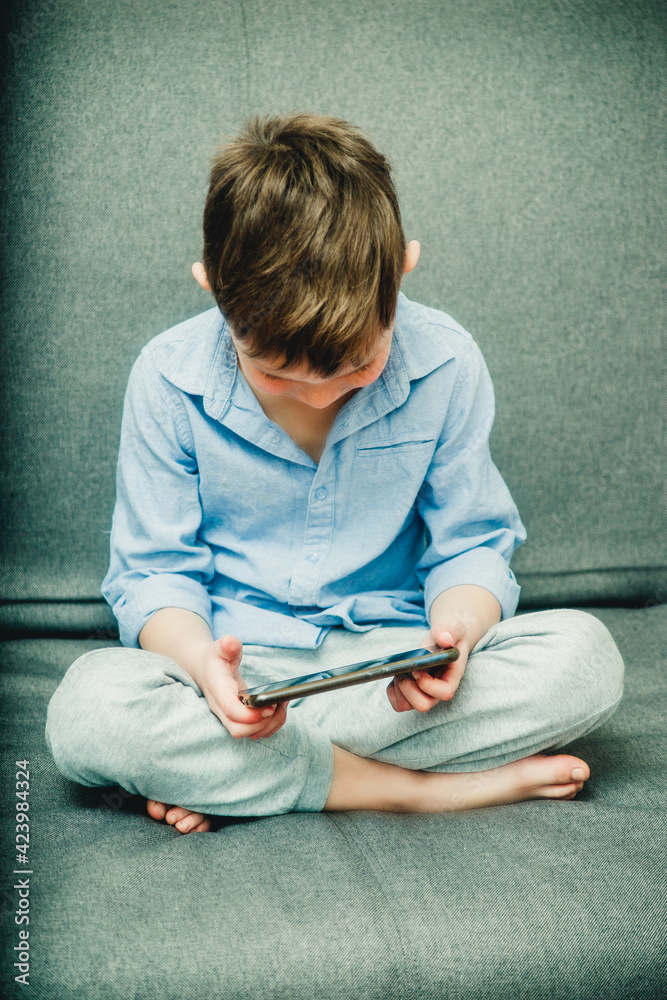 Fototapeta premium boy on the couch with a phone