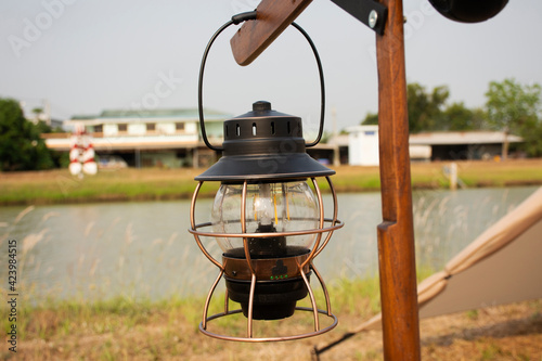 Antique retro vintage Kerosene lamp or burning oil lantern on pole for tent camping on grass park beside irrigation canal at Bangbuathong city rural countryside of Nonthaburi in Nonthaburi, Thailand photo