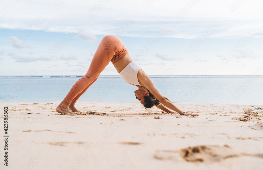 Flexible woman practicing yoga asana on shore Flexible woman practicing yoga asana on shore