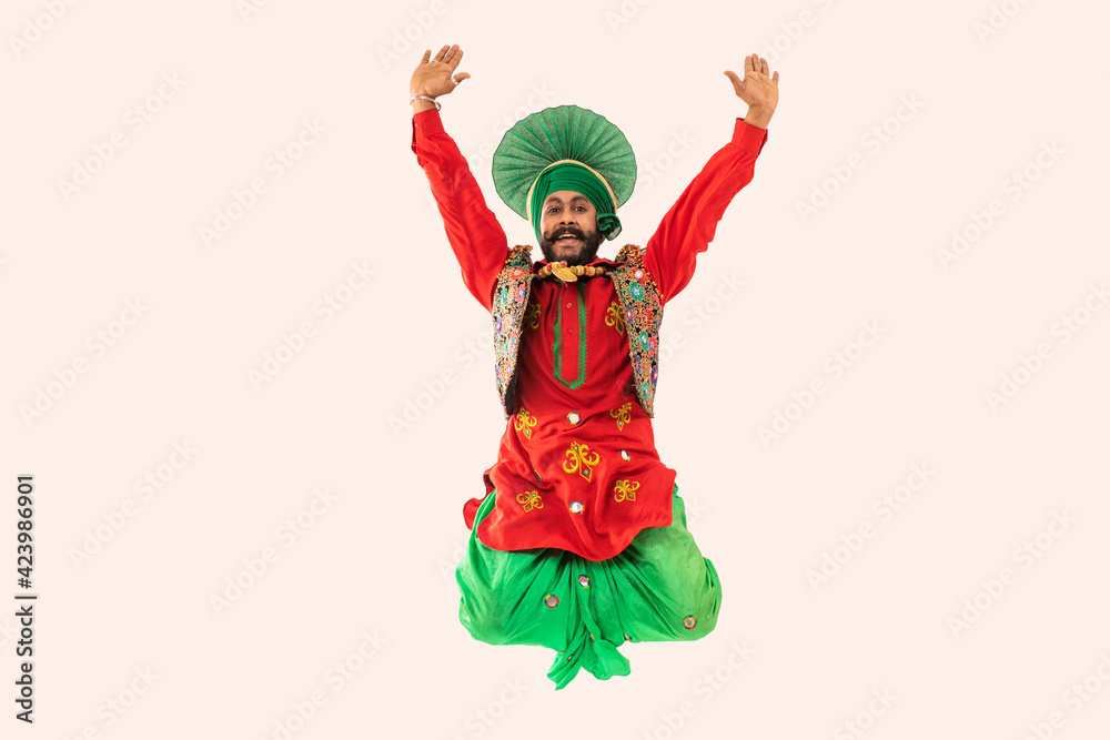 A Bhangra Dancer jumping with hands up to show a dance step.	