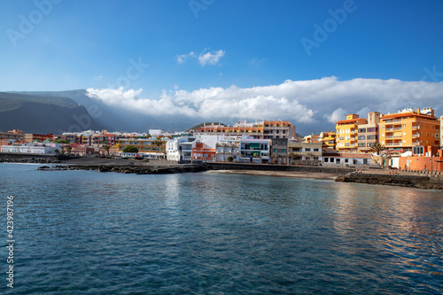 tranquil town on the eastern coast of the island with a small neat beach and calm and smooth waves, with few people passing by in Puertito de Guimar, Tenerife, Canary Islands, Spain