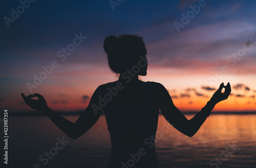 Young woman standing on seashore during sunset