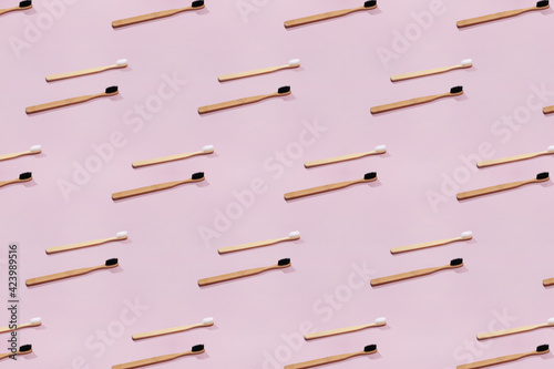 Pattern with wooden tooth brushes on pink background.