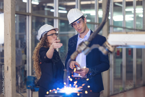 Engineer supervising autonomous producton process industry robot arm in factory photo