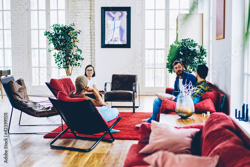 Canvas Print Multicultural group of youthful hipster guys communicating during weekend meetin