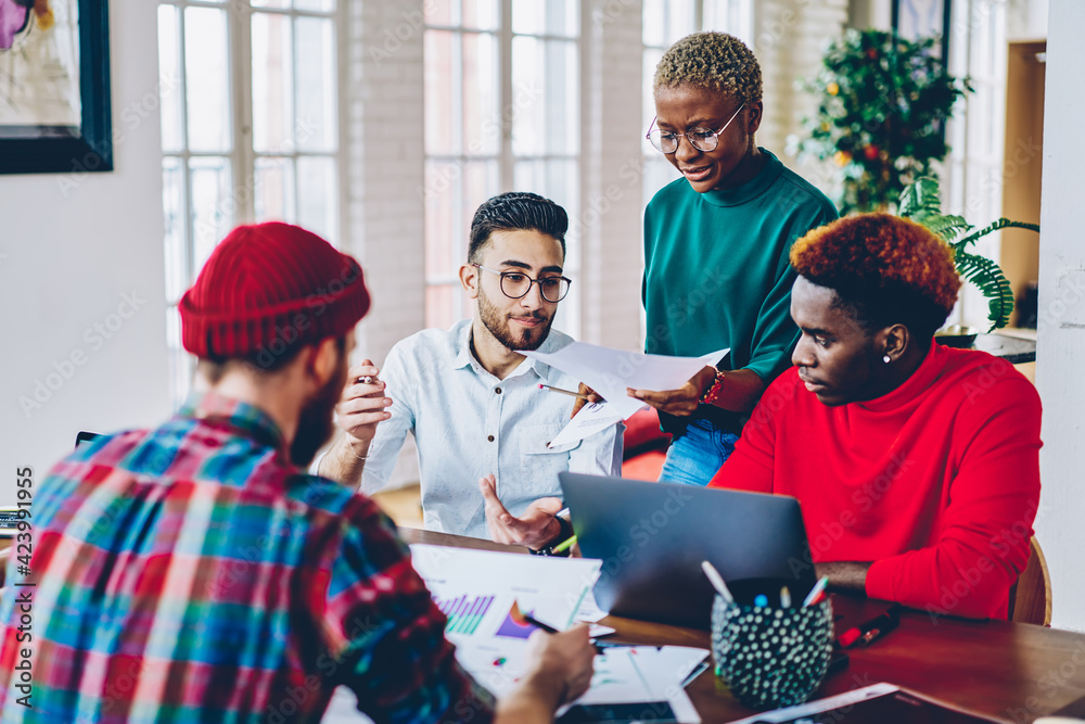 Multicultural team of male and female designers collaborating on ...