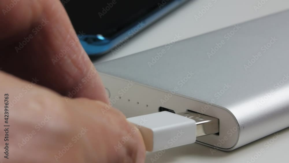 Powerbank external battery charging smartphone lying on the table. The indicator flashes. 