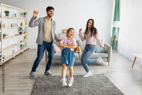 Funny leisure activities. Overjoyed eastern family moving and dancing to music with his child
