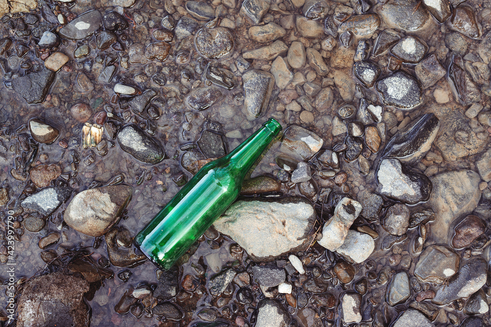 Glass bottle at river coast, top view. Water pollution concept. Contamination of the environment by humans. Glass bottle at river coast, top view. Water pollution concept. Contamination of the environment by humans.