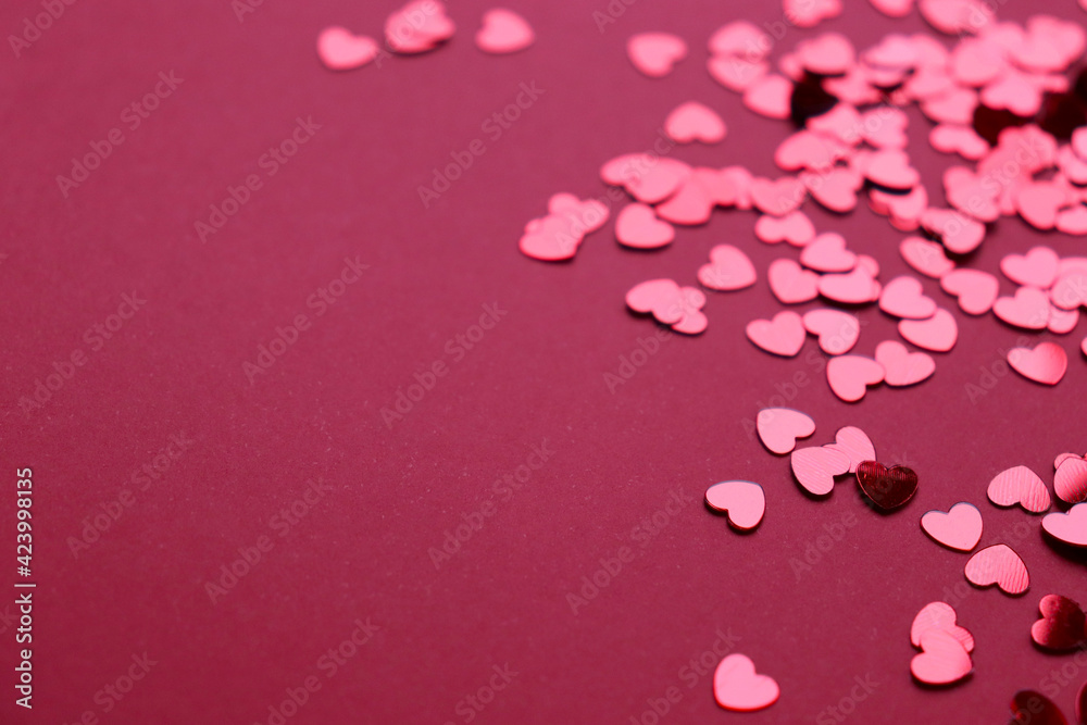 Sparkling confetti in the shape of a heart is scattered on a red background. The concept of love. A greeting card. Valentine's Day
