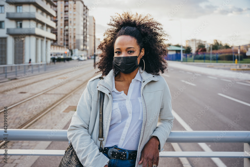 Obraz premium Portrait of a young woman in the evening at sunset in the city wearing protective face mask during the global pandemic from Covid-19 Coronavirus