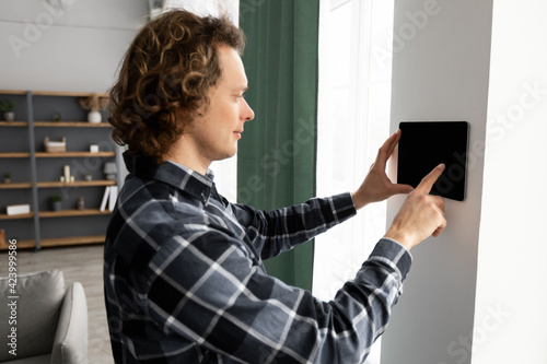 Man Using Smart Home Control System On Digital Tablet Indoors