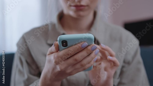 Close up hands woman hold use phone at home sitting on sofa in modern room. Social media, girl, technology, mobile, online, typing, business, communication. Slow motion