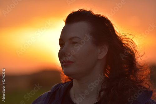 portrait of a red-haired woman in the evening against a sunset