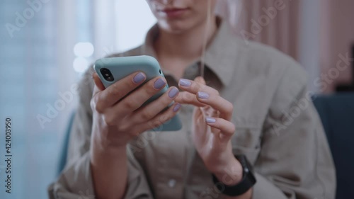 Young hands woman hold use phone at home sitting on sofa in modern room. Social media, girl, technology, mobile, online, typing, business, communication. Slow motion