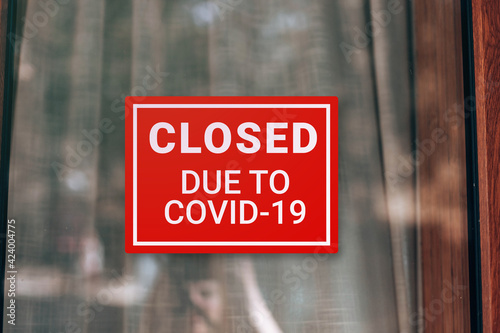 Close up on closed sign in the window of a shop with inscription Closed due to Covid-19. Coronavirus outbreak lockdown