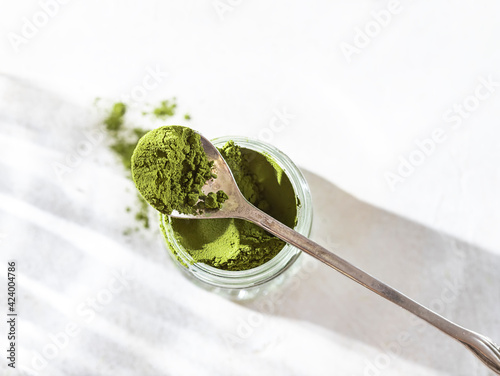 Green powder chlorella, spirulina on gray concrete background. Concept dieting, detox, healthy superfood, which contains protein.