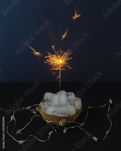 melting ice in coconut with sparklers on dark background