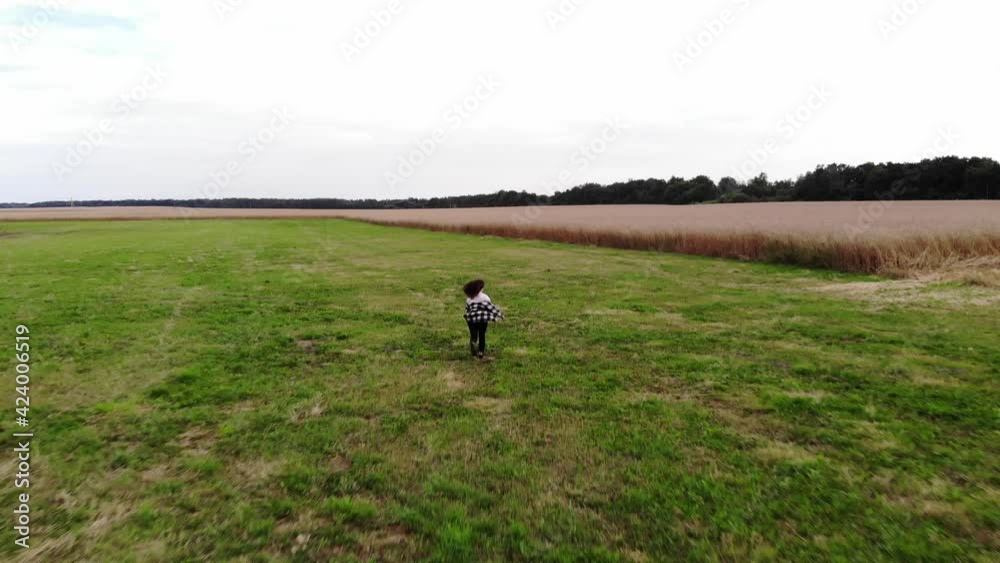 Drone shooting of a beautiful landscape in the countryside and a young girl running to a wheat field Drone shooting of a beautiful landscape in the countryside and a young girl running to a wheat field