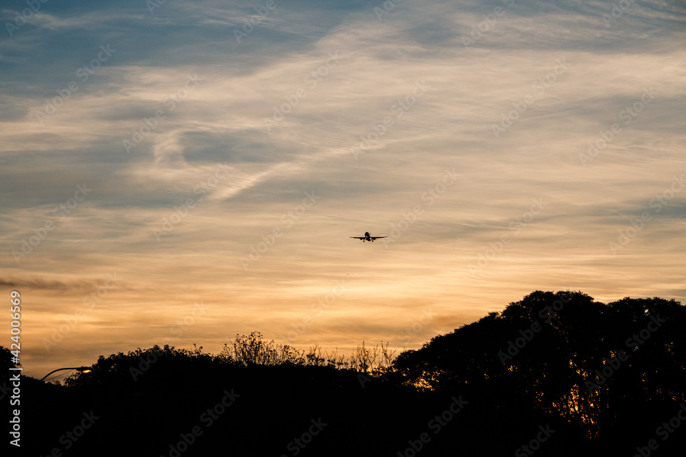 A plane coming from a fire sky in a lovely afternoon