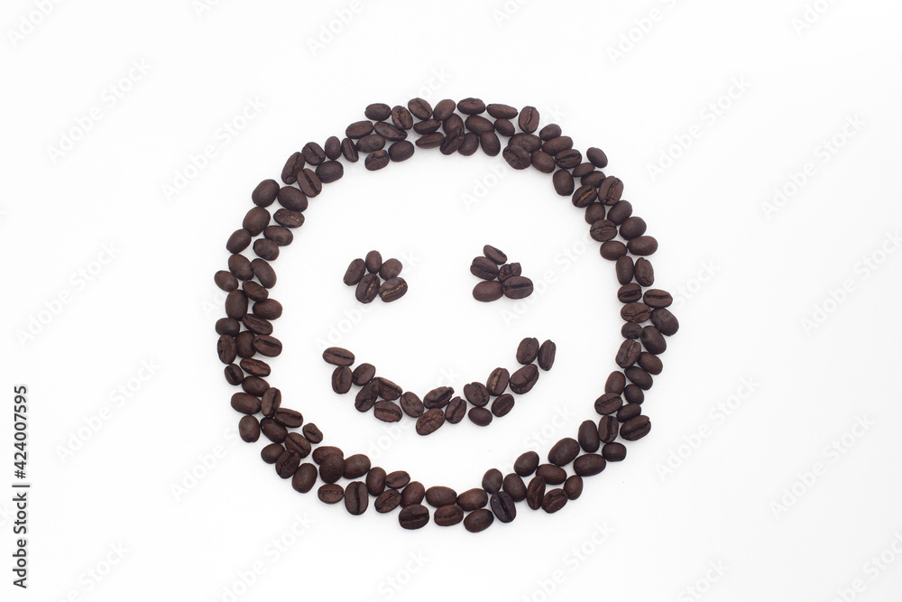 Roasted coffee beans arranged in a smiling face on a white background. Roasted coffee beans arranged in a smiling face on a white background.
