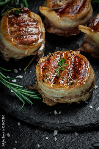 Medallions steaks from the beef tenderloin covered bacon on Dark background. Top view vertical image