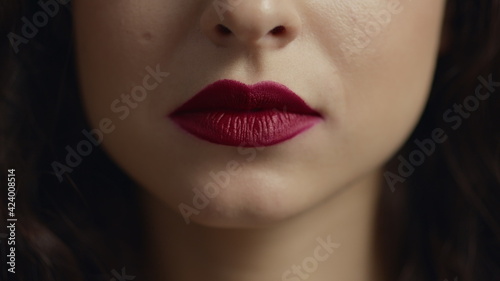 Close up of unrecognizable girl face licking red plump lip with tongue.