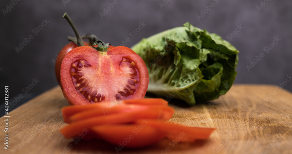 Tomatoes in slices and lettuce on a wooden board - studio photography Tomatoes in slices and lettuce on a wooden board - studio photography