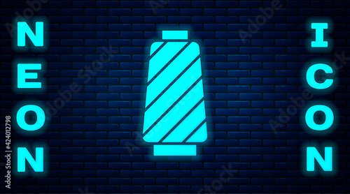 Glowing neon Sewing thread on spool icon isolated on brick wall background. Yarn spool. Thread bobbin. Vector