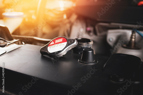The radiator cap 1.1 bar is open and placed on radiator of the car engine with a sunlight