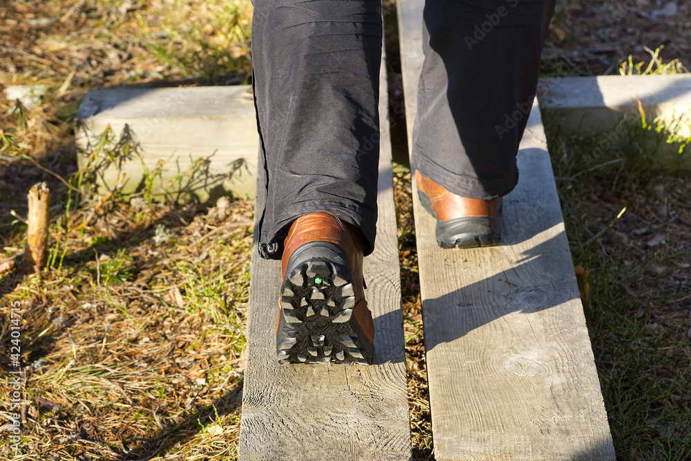 Man walking on a boardwalk in the woods and enjoys hiking in spring or autumn Man walking on a boardwalk in the woods and enjoys hiking in spring or autumn