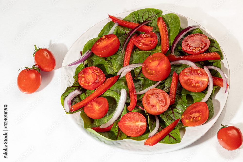 Vegetarian salad of cherry tomatoes, spinach, red onions and bell peppers with butter. On a white background. Isolate. Vegetarian salad of cherry tomatoes, spinach, red onions and bell peppers with butter. On a white background. Isolate.