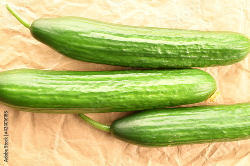 Three green cucumbers, close-up, on craft paper, top view.