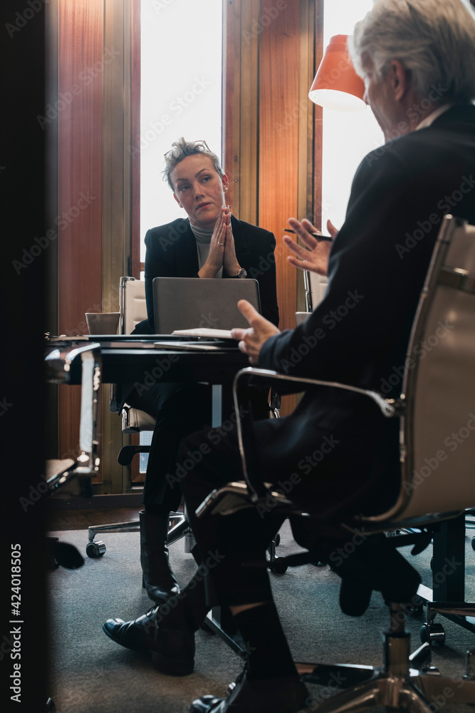 Senior businessman planning strategy with businesswoman at conference table in board room Senior businessman planning strategy with businesswoman at conference table in board room