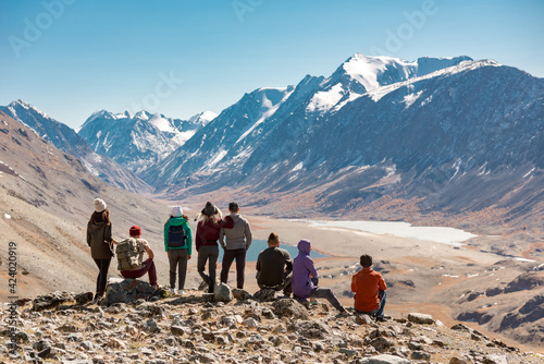 Big group of peoples, tourists or friends are standing on view point in mountains and enjoying photo